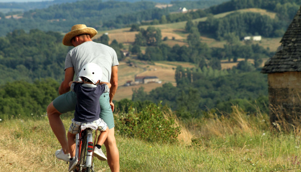 homme en vélo avec un enfant sur son porte-bébé