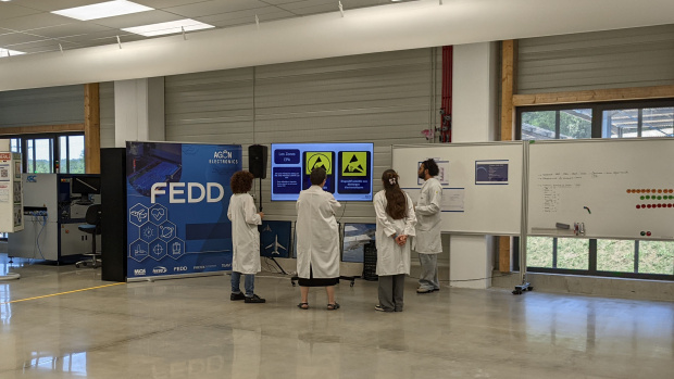 trois personnes de l'usine travaillant sur des visuels présentés sur des tableaux