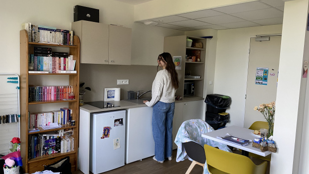 jeune fille devant sa kitchenette de son logement