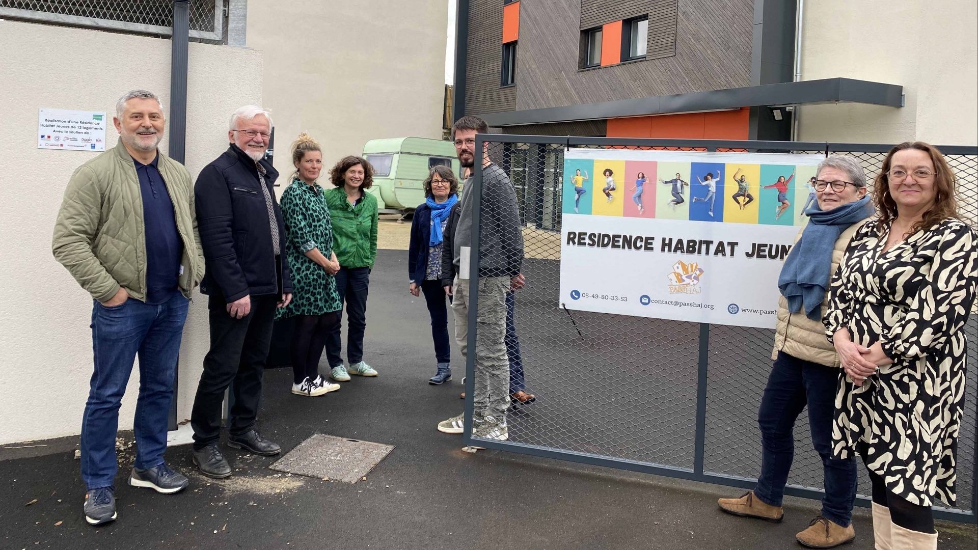 Personnes en charge du projet posant fièrement devant l'enseigne du logement