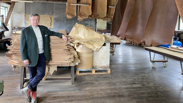 président de la tannerie devant de nombreux morceaux de cuir
