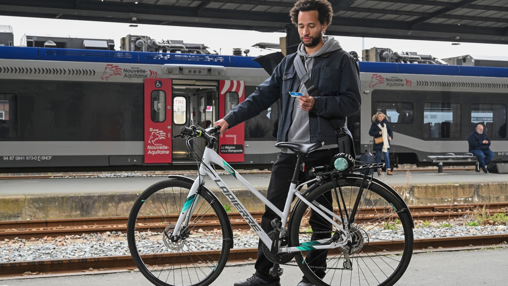 un homme avec son vélo attendant son train à la gare